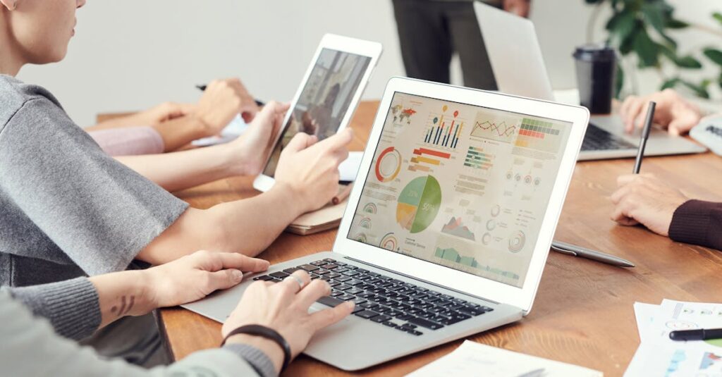 Coworkers analyzing data charts on laptops during a team meeting.